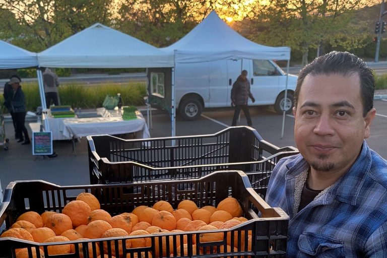 A man stands with oranges.