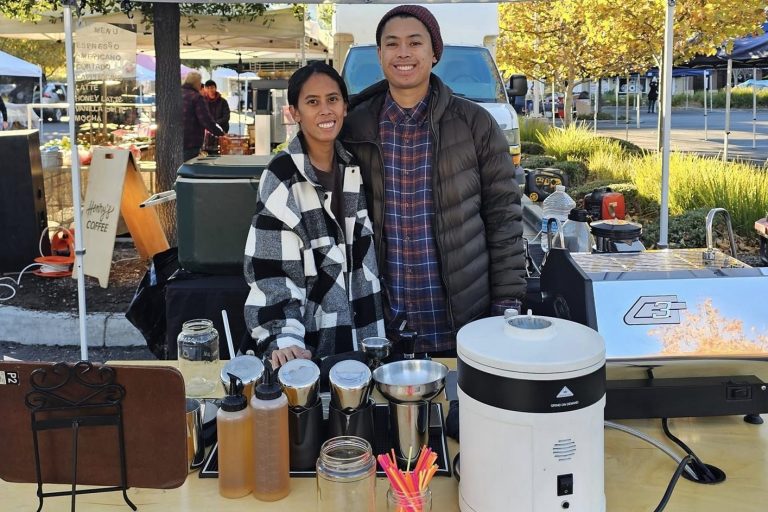 A man and woman pose with coffee equipment.