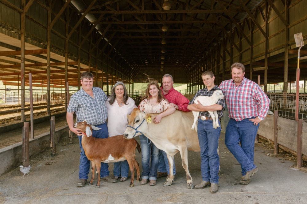 A family in a barn with their animals.