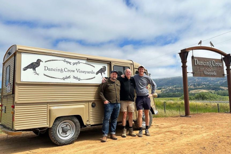 Three farmers in front of a company van.